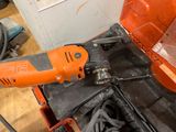 an orange and black electric drill in a tool box