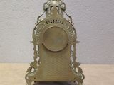 a gold clock sitting on a table in front of a white wall