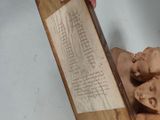 a person holding a wooden plaque with a drawing on it