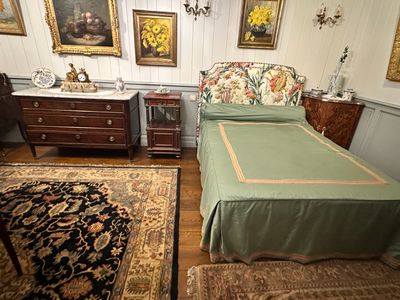 a bed with a green cover in a room with pictures on the wall