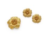 three gold flower brooches on a white background