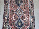 un tapis persan ancien aux motifs bleus, rouges et verts