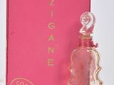 une image représentant un flacon de parfum posé à côté d'une boîte rose