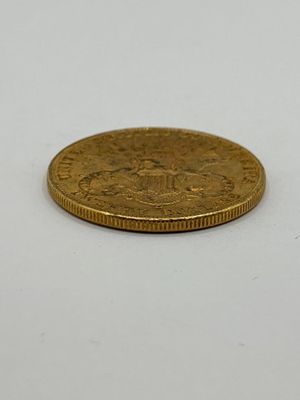 gros plan d'une pièce d'or sur une surface blanche