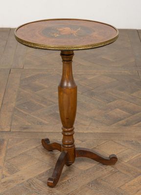 une vieille table en bois au plateau rond, posée sur un parquet
