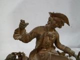 une statue en bronze d'un homme assis sur un bateau