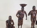 three figurines of a man and a woman with a bowl on their head