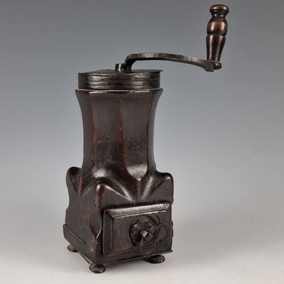 an antique coffee grinder with a wooden handle on a gray background