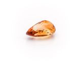 a close up of an orange sapphire stone on a white surface
