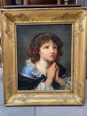portrait d'une jeune fille en robe bleue, les mains jointes devant le visage