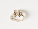 une image représentant une bague en diamant et en or posée sur une surface blanche