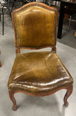 un fauteuil en cuir marron placé dans une pièce, à côté d'une table