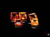 two pieces of yellow and orange colored glass sitting on top of a black surface