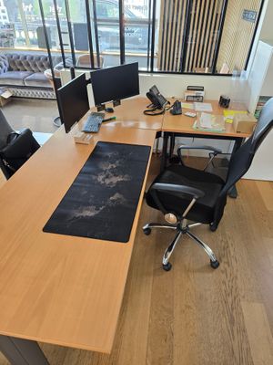 un bureau avec deux ordinateurs et une chaise devant une fenêtre