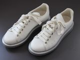 une paire de baskets blanches posées sur une surface noire, sur fond noir