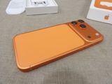 an orange iphone sitting on a table next to a white box
