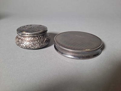 un petit objet en argent posé à côté d'un autre objet en argent, plus petit