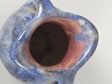 a blue vase that has a black hole in it