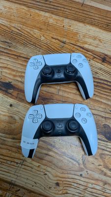 deux manettes de jeux vidéo posées sur un parquet