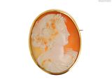 Une broche plaquée or représente le profil d'une femme.