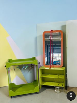 une étagère verte sur laquelle est posé un miroir, à côté d'une chaise verte