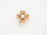 a gold flower brooch with a pearl in the center
