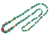 un gros plan d'un long collier orné de perles vertes sur fond blanc
