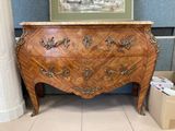 une commode en bois dans une pièce où est accroché un tableau au mur