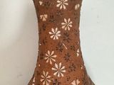 a brown vase with flowers on it sitting on a table
