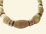 a close up of a gold necklace on a white background