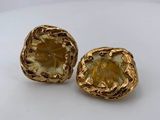 a pair of goldtone earrings on a white surface