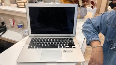 a woman standing next to a laptop computer on a table
