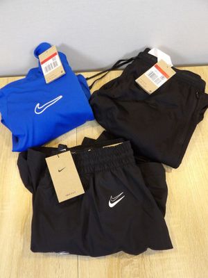 trois paires de shorts Nike noirs et bleus posés sur un parquet