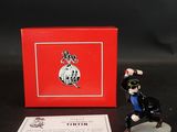 La figurine est posée à côté d'une boîte rouge sur une table noire.