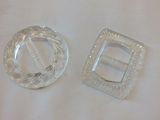 two clear plastic buckles on a white surface