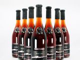 six bottles of wine are lined up in a row on a white surface