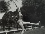 black and white photograph of a woman in a bathing suit doing a trick