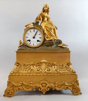 an image of a gold clock with a woman sitting on top of it