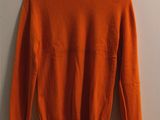 an orange sweater hanging on a wall next to a hanger