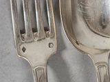 two silver spoons and a fork on a table