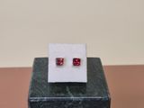 a pair of red stone earrings sitting on top of a marble block