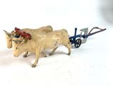 a toy of a cow pulling a cart with a man on it