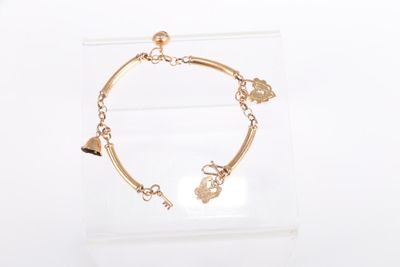 bracelet plaqué or avec des breloques, présenté dans un coffret transparent