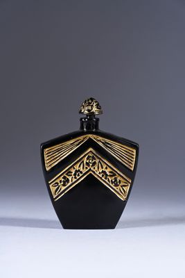 a black and gold perfume bottle sitting on top of a white surface