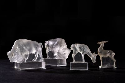 three clear glass figurines of animals on a black surface