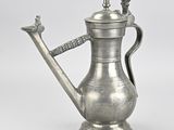 an antique silver coffee pot with a handle on a white background