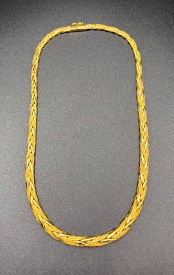 a close up of a gold necklace on a black surface