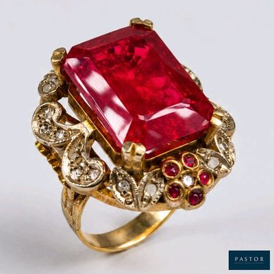 une image représentant une bague ornée d'une pierre rouge entourée de diamants