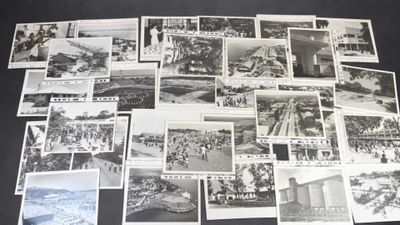 plusieurs photographies en noir et blanc représentant des personnes et des bâtiments, posées sur une table