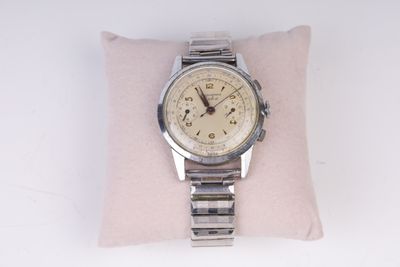 une montre posée sur un oreiller, sur une surface blanche